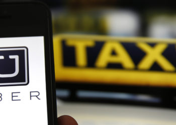 File illustration picture showing the logo of car-sharing service app Uber on a smartphone next to the picture of an official German taxi sign in Frankfurt, September 15, 2014. A Frankfurt court earlier this month instituted a temporary injunction against Uber from offering car-sharing services across Germany. San Francisco-based Uber, which allows users to summon taxi-like services on their smartphones, offers two main services, Uber, its classic low-cost, limousine pick-up service, and Uberpop, a newer ride-sharing service, which connects private drivers to passengers - an established practice in Germany that nonetheless operates in a legal grey area of rules governing commercial transportation.    REUTERS/Kai Pfaffenbach/Files  (GERMANY - Tags: BUSINESS EMPLOYMENT CRIME LAW TRANSPORT)