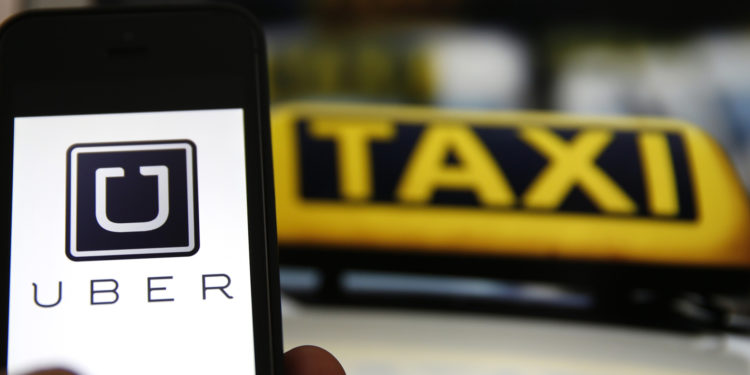 File illustration picture showing the logo of car-sharing service app Uber on a smartphone next to the picture of an official German taxi sign in Frankfurt, September 15, 2014. A Frankfurt court earlier this month instituted a temporary injunction against Uber from offering car-sharing services across Germany. San Francisco-based Uber, which allows users to summon taxi-like services on their smartphones, offers two main services, Uber, its classic low-cost, limousine pick-up service, and Uberpop, a newer ride-sharing service, which connects private drivers to passengers - an established practice in Germany that nonetheless operates in a legal grey area of rules governing commercial transportation. REUTERS/Kai Pfaffenbach/Files (GERMANY - Tags: BUSINESS EMPLOYMENT CRIME LAW TRANSPORT)