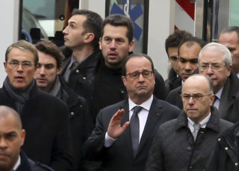 French President Francois Hollande, center, flanked with security forces gestures, as he arrives outside the French satirical newspaper Charlie Hebdo's office, in Paris, Wednesday, Jan. 7, 2015. Masked gunmen stormed the offices of a French satirical newspaper Wednesday, killing at least 11 people before escaping, police and a witness said. The weekly has previously drawn condemnation from Muslims. (AP Photo/Remy De La Mauviniere)