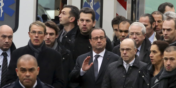 French President Francois Hollande, center, flanked with security forces gestures, as he arrives outside the French satirical newspaper Charlie Hebdo's office, in Paris, Wednesday, Jan. 7, 2015. Masked gunmen stormed the offices of a French satirical newspaper Wednesday, killing at least 11 people before escaping, police and a witness said. The weekly has previously drawn condemnation from Muslims. (AP Photo/Remy De La Mauviniere)