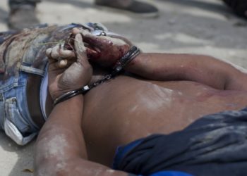 A man's body with his bloodied hands handcuffed lays at a crime scene in Tabarre, a town on the outskirts of Port-au-Prince, Haiti, early Friday, May 1, 2015. Investigators removed three bodies, found handcuffed and blindfolded, from a car that was parked on the side of a street surrounded by open land, and about three blocks from the U.S. embassy. According to police investigators on the scene, the people found dead are Gerda Julien, her brother Robernard Julien and Carl Eduard Guerrier. (AP Photo/Dieu Nalio Chery)