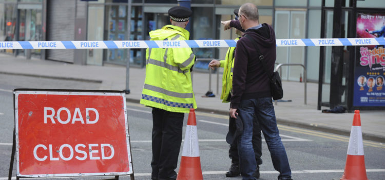Police block a road near to the Manchester Arena in central Manchester, England Tuesday, May 23, 2017. An explosion struck an Ariana Grande concert attended by thousands of young music fans in northern England late Monday, killing over a dozen people and injuring dozens in what police said Tuesday was being treated as a terrorist attack. (AP Photo/Rui Vieira)