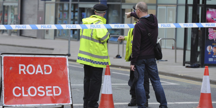 Police block a road near to the Manchester Arena in central Manchester, England Tuesday, May 23, 2017. An explosion struck an Ariana Grande concert attended by thousands of young music fans in northern England late Monday, killing over a dozen people and injuring dozens in what police said Tuesday was being treated as a terrorist attack. (AP Photo/Rui Vieira)