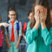 Schoolgirl crying on background of classmates teasing her