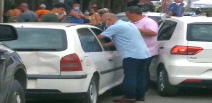 José Carlos de Oliveira é visto aplicando a vacina em uma das vias da cidade, acompanhado por um homem que carrega um isopor com as doses.