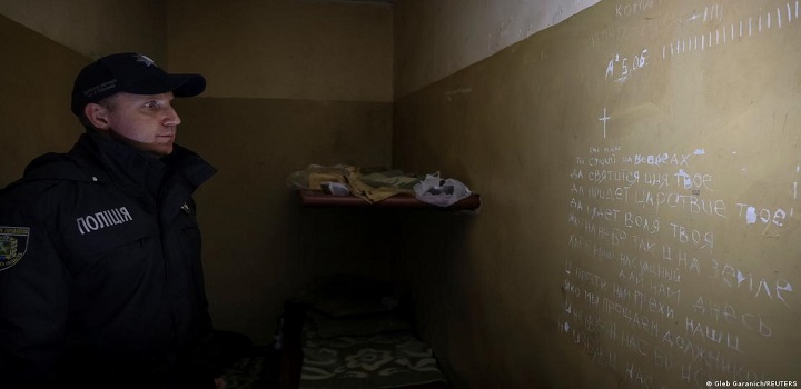 Policial observa número de dias e uma oração rabiscados na parede do porão de um escritório de polícia, usado por militares russos como local de detenção na cidade de BalakliiaFoto: Gleb Garanich/REUTERS