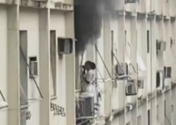 Mulher se abriga na área externa de prédio após incêndio atingir apartamento em Copacabana, na Zona Sul do Rio.